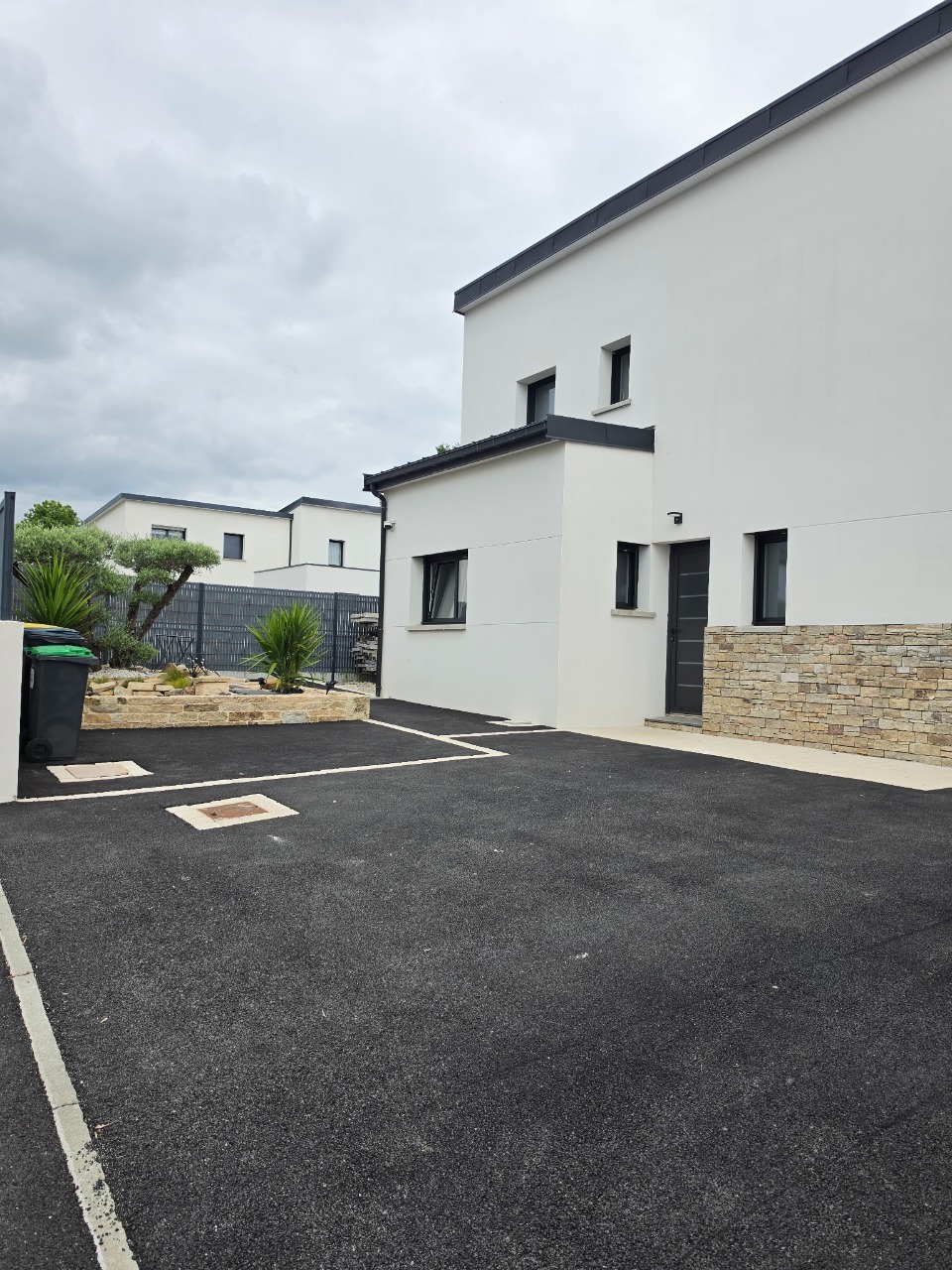 Aménagement extérieur — Enrobé, muret en pierre et plantations méditerranéennes chez Frédéric à Caudan